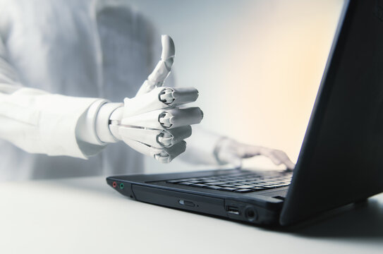 Close-up of Robot Hand Giving Thumbs Up Gesture near Laptop for AI Success Concept