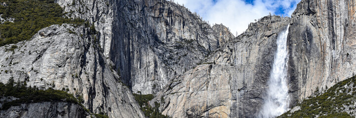 Bridalveil Fall cascades down towering granite cliffs in Yosemite National Park, California. Fresh snowfall blankets the surrounding Sierra Nevada peaks beneath dramatic blue skies and towering clouds © Gerard