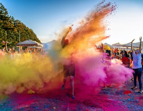 vibrant explosion of colored powder fills the air during a joyful celebration showcasing a stunning mix of pink yellow and blue hues at an outdoor festival in bright daylight