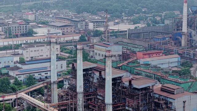 Aerial slow push in shot of a heavy industry plant under gloomy overcast sky, ideal for corporate videos and environmental documentaries.