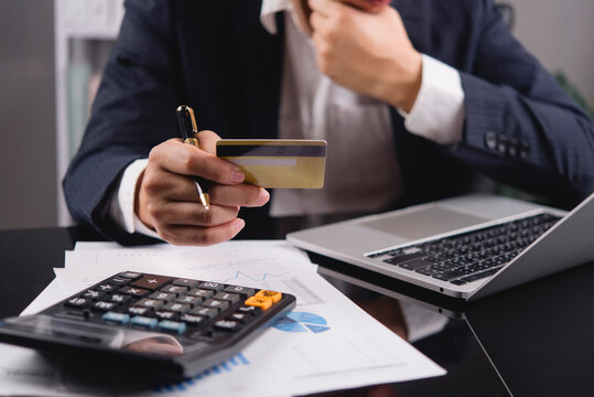businessman hands holding credit card using calculator and laptop. Corporate finance, online payment, business transaction, e-commerce shopping and budget calculation concept at desk.