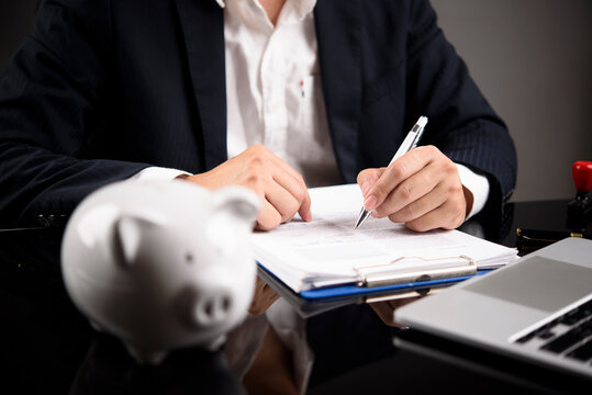 businessman signing financial document piggy bank foreground office desk saving money investment planning wealth management corporate finance banking loan agreement retirement insurance accounting