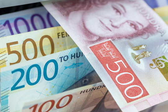 Swedish Krona versus Norwegian Krone banknotes inside currency counter machine. Scandinavian markets financial analysis, exchange rate and banking business background.