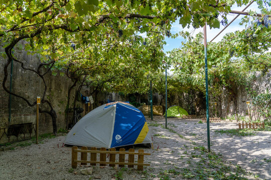 Verona Italy - September 1 2025: A Campsite With Tents Under Grape Vines in a Historic Castle Verona Italy