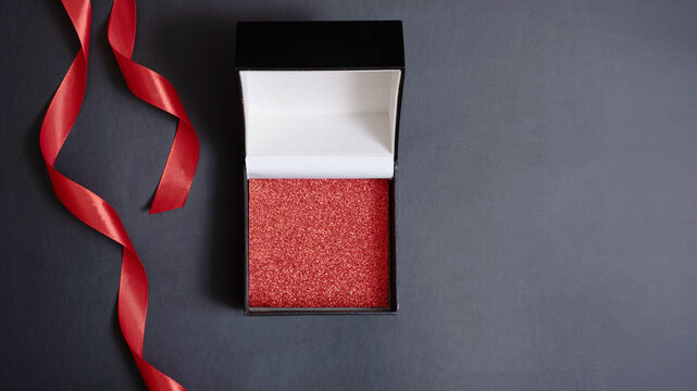 Black friday sale concept. Black gift box with copy space and festive decorations on black background flat lay, top view.