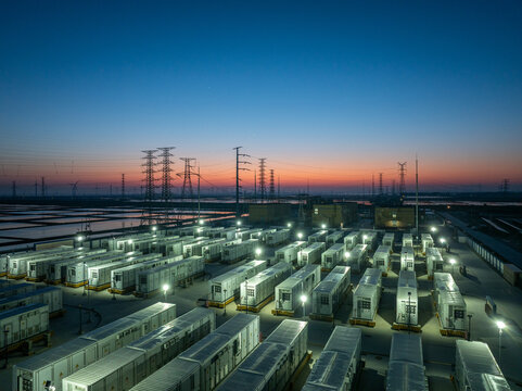 Energy storage power station with container arrays illuminated at dusk under twilight sky