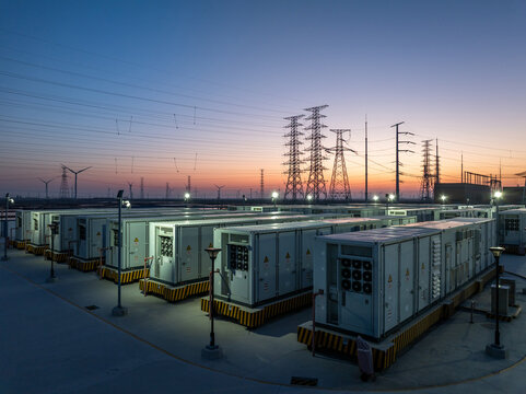 Energy storage power station equipment array and transmission towers at dusk