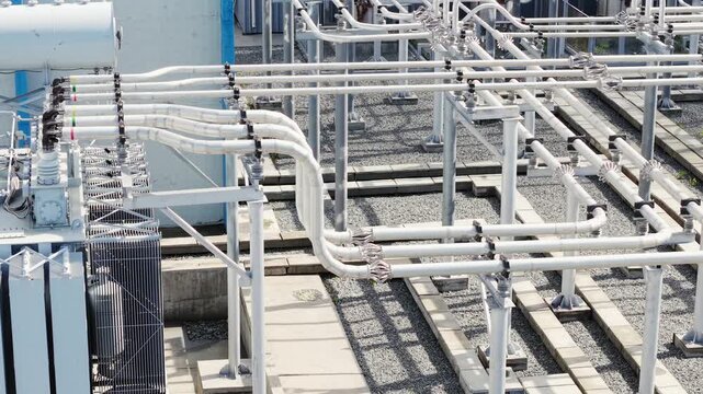 Aerial view showing electrical transformer and busbar connections being routed across outdoor substation rooftop.