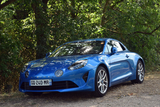 St- Amand Montrond - France - 2 August 2026 - Three quarter front side view of a blue Alpine A110 sports car parked at the edge of a forest