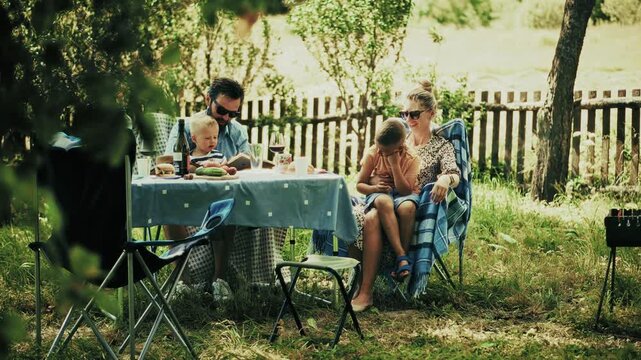 Family Having Picnic In Backyard Garden. Eating Together Outdoor Summer. Childhood Happiness And Togetherness 