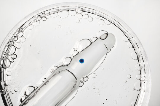 Glass ampoule with medicine in petri dish with bubbles, close-up