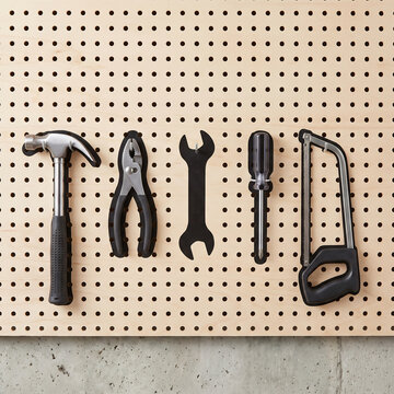 Garage pegboard with hand tools hanging over painted silhouette outlines and one empty slot