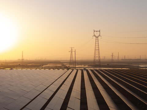 Solar power station and transmission towers at sunrise with orderly photovoltaic arrays and metallic structures
