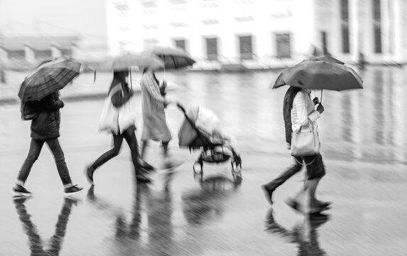 Blurred image of people with umbrellas in the rain