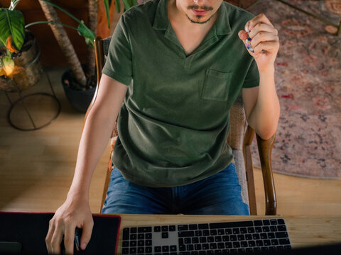 Man squeezing stress ball while working on computer at home 