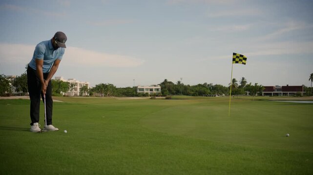 African american man chipping a golf ball with a wedge club near the putting green