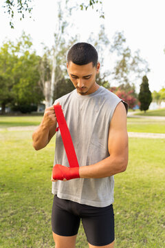 Young Man Wraps Hands Before Training in Park