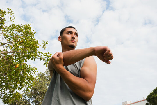 Man Stretching His Arms Outdoors Under a Cloudy Sky
