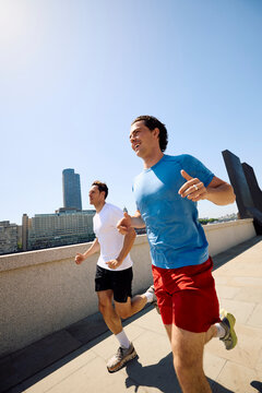 Active men run by the Thames River in London