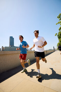 Active men run alongside London's Thames River
