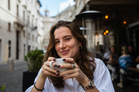 Young woman enjoying a coffee at a sidewalk caf&eacute; in Rome