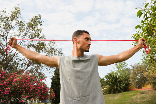 Man Exercises With Resistance Band in Park During Daylight