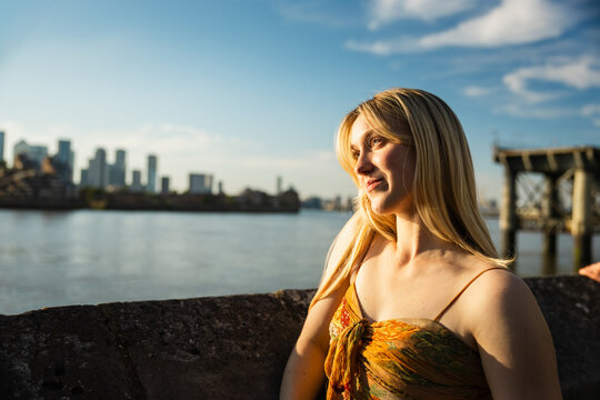 Young woman gazing thoughtfully by the Thames at golden hour