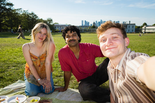 Friends taking a group selfie during a picnic in London