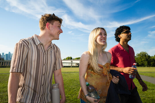 Happy young friends walking together in a sunny park