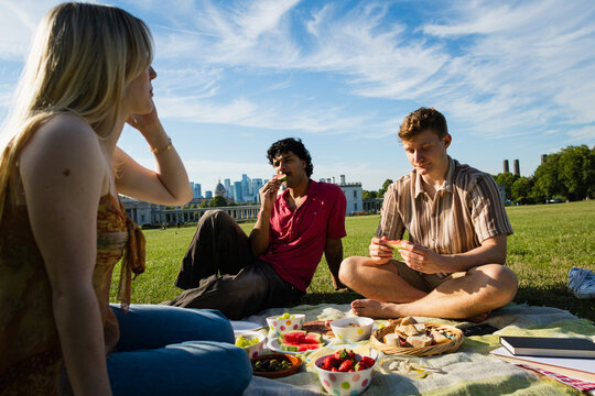 Friends eating fruit at a picnic with London skyline background