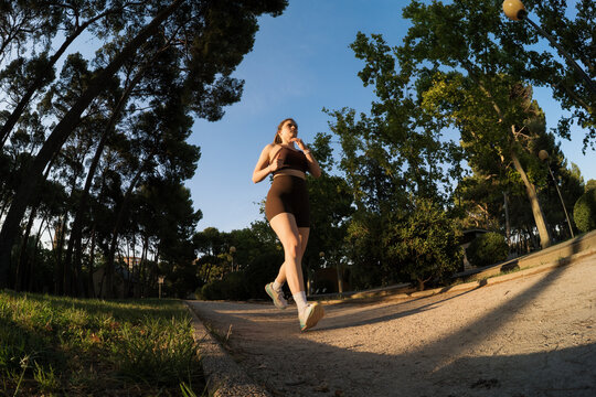 Woman runs on a path under a clear blue sky during evening hours