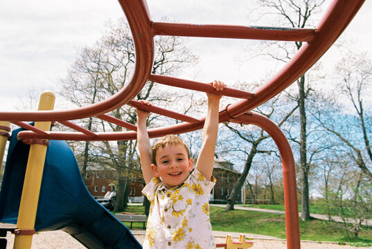 Candid moment of child swinging on monkey bars at playground