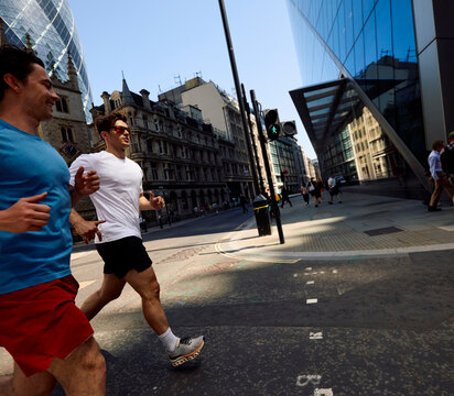 Men jog alongside each other on a street in downtown London.