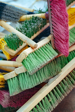 Colorful brooms are stacked together in a work area