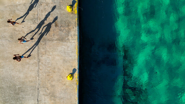 Children running on dock casting long shadows