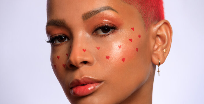 Creative makeup for Valentines day. Portrait of female fashion model isolated on white studio background. Beautiful woman with spring makeup in the shape of small hearts. Beauty concept.