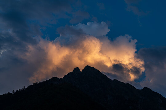 Dramatic sky with clouds and silhouette of a mountain peak at sunset in summer