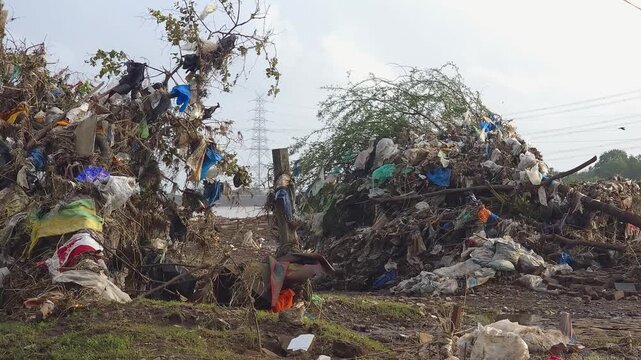 A large accumulation of plastic waste, household garbage, and debris dumped along a riverside, highlighting the growing issue of environmental pollution and poor waste management.