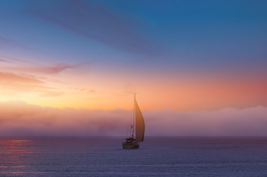 Lonely yacht sailing in the Mediterranean sea at amazing sunset - Sailing luxury yacht with white sails in the Sea.