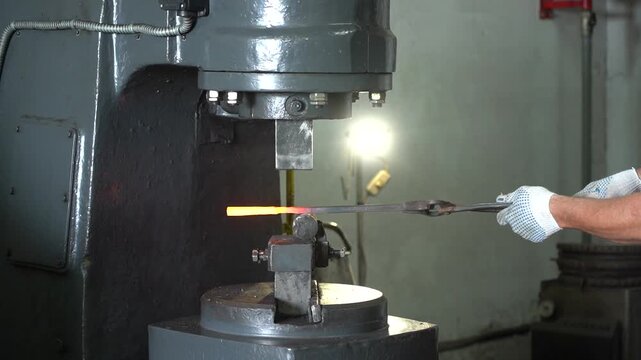 Crafting Metal: The High-Speed Action of a Hydraulic Press Forging a Hot Iron Bar into Shape at a Workshop, Showcasing Metalworking Techniques and Precision