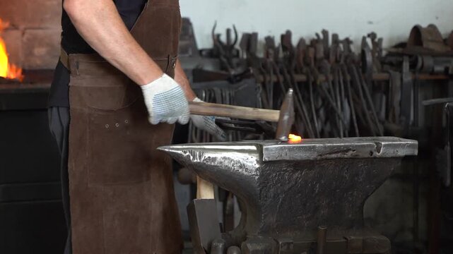 Craftsman in Action: A Skilled Blacksmith Forging Metal with Precision at the Anvil, Highlighting the Art of Traditional Metalworking in a Workshop Setting