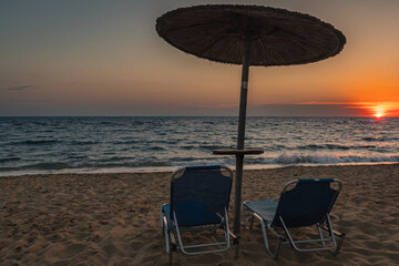 Empty beach chairs under parasol at sunset on the Greek coast © PolgarCsabaPhoto