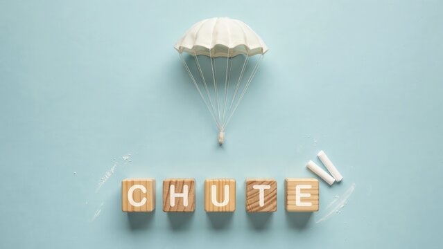 Conceptual flat lay of wooden blocks spelling 'CHUTE' with a parachute, representing controlled descent and safety planning
