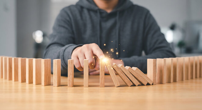 Fingertip Pushing First Domino, Causing Chain Reaction and Sparking Effect, Symbolizing Cause and Effect, Impact, and Momentum. Finger touch on block concept.
