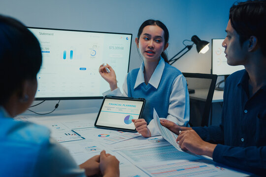 Asia businesspeople presentation sales meeting plan analysis statistics brainstorm and tablet point graph chart take note in office conference room at night. Business finance partner strategy success.