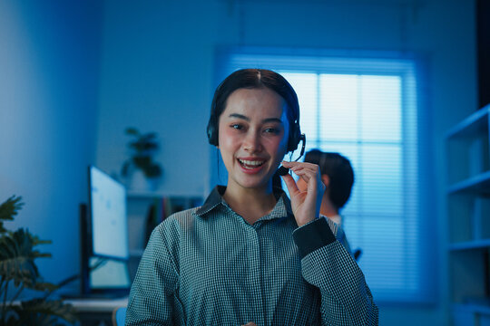 Gen z Asia young call center team or customer support service executive use computer and microphone headset work technical e commerce support in late night office. Telemarketing or sales job concept.