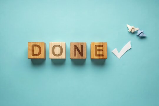 Word Done on Wooden Blocks with Checkmark and Paper Butterflies on Blue Background