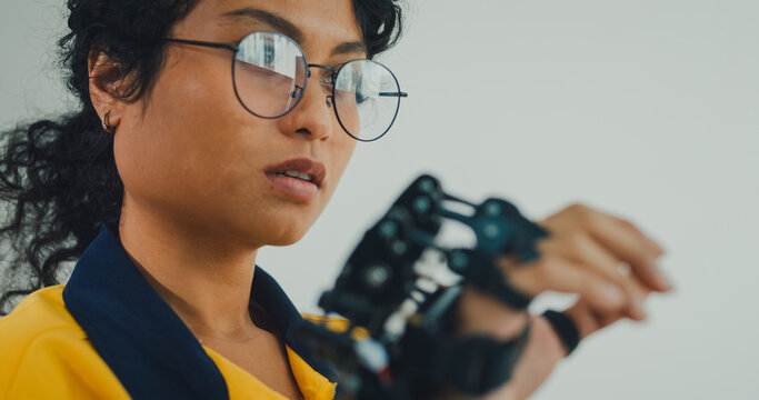 Close-up young Black female engineer coding AI robot arm in modern laboratory. Robotics, artificial intelligence, technology, stem, future, innovation, diversity, automation, machine learning concept.