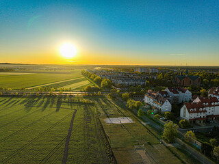 Słoneczny zachód nad zielonymi polami i zabudową Leszna – panorama z drona © Vladyslav Riadov