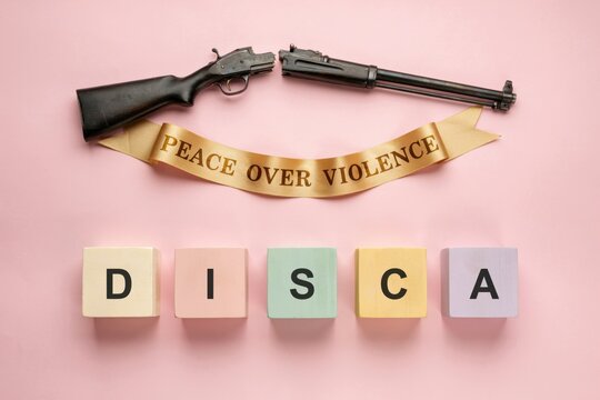 Concept of Peace Over Violence with Disarmed Weapons and Ribbon on Pink Background